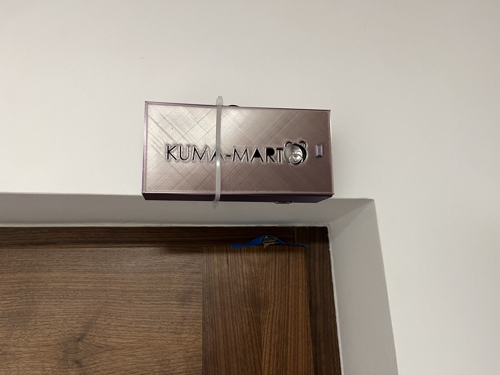 A small box with the door chime inside, strapped above the front door frame