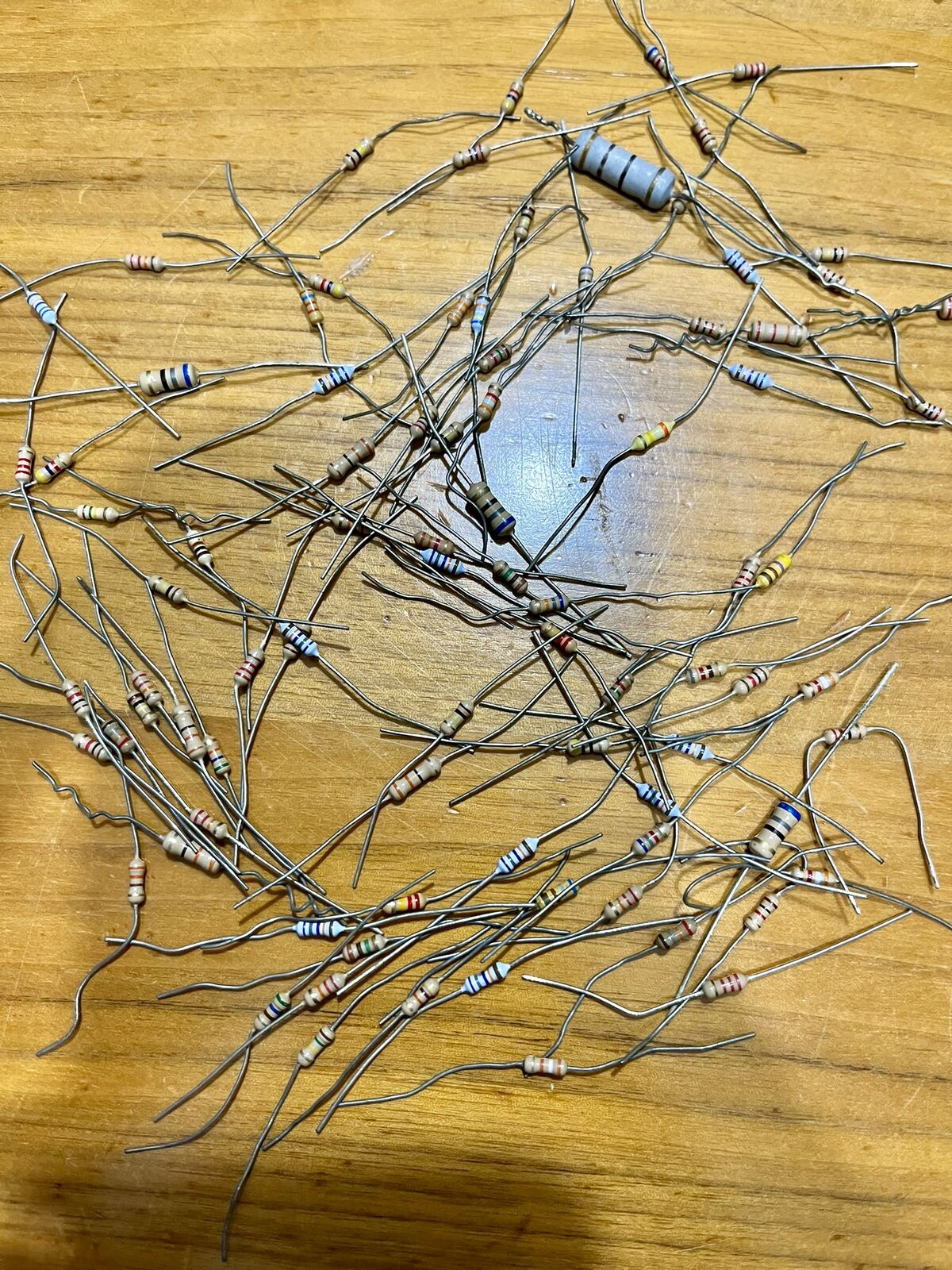 A tangled pile of unlabelled resistors on a wooden table