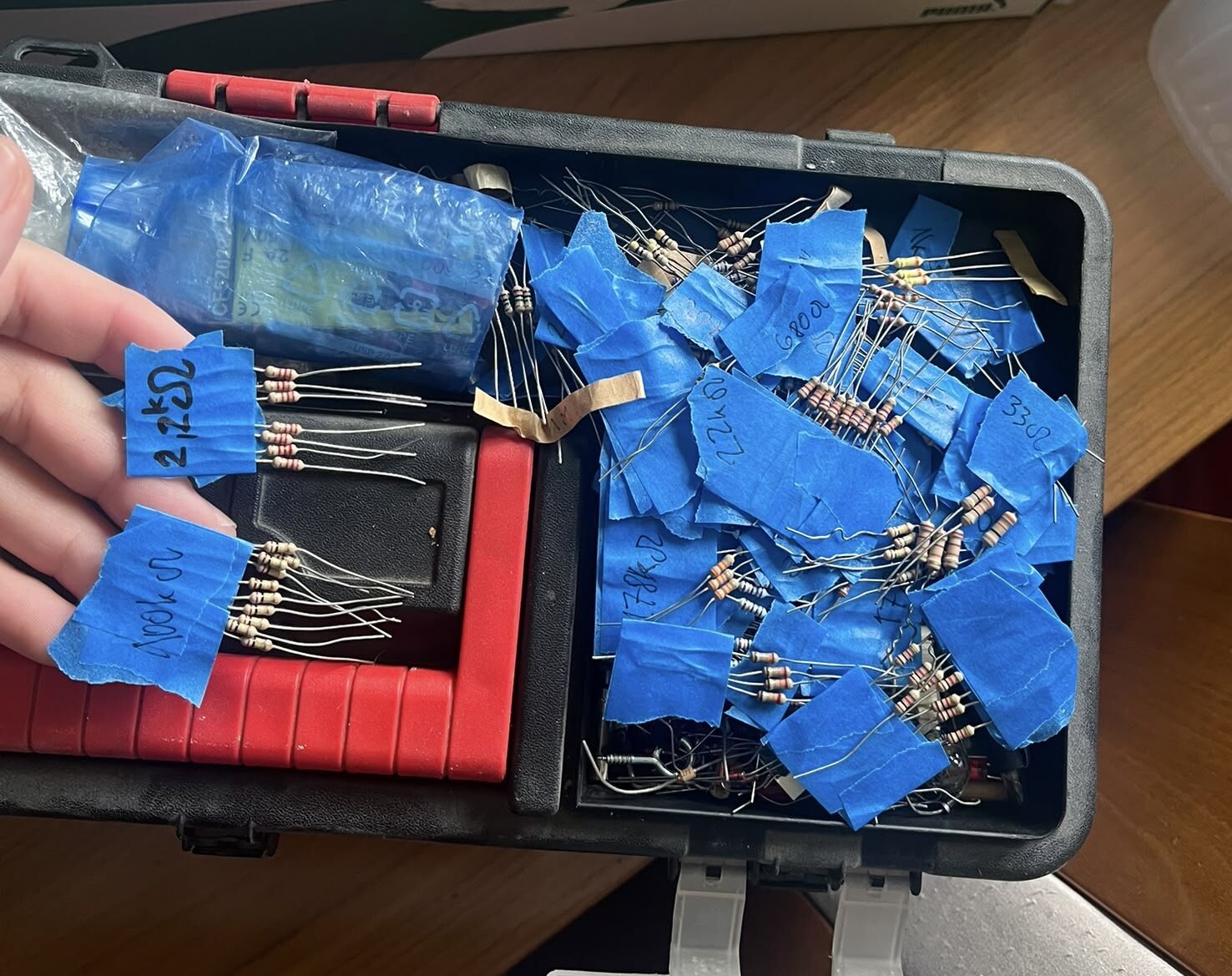 The same resistors sorted into a box, each bundle labelled with blue tape